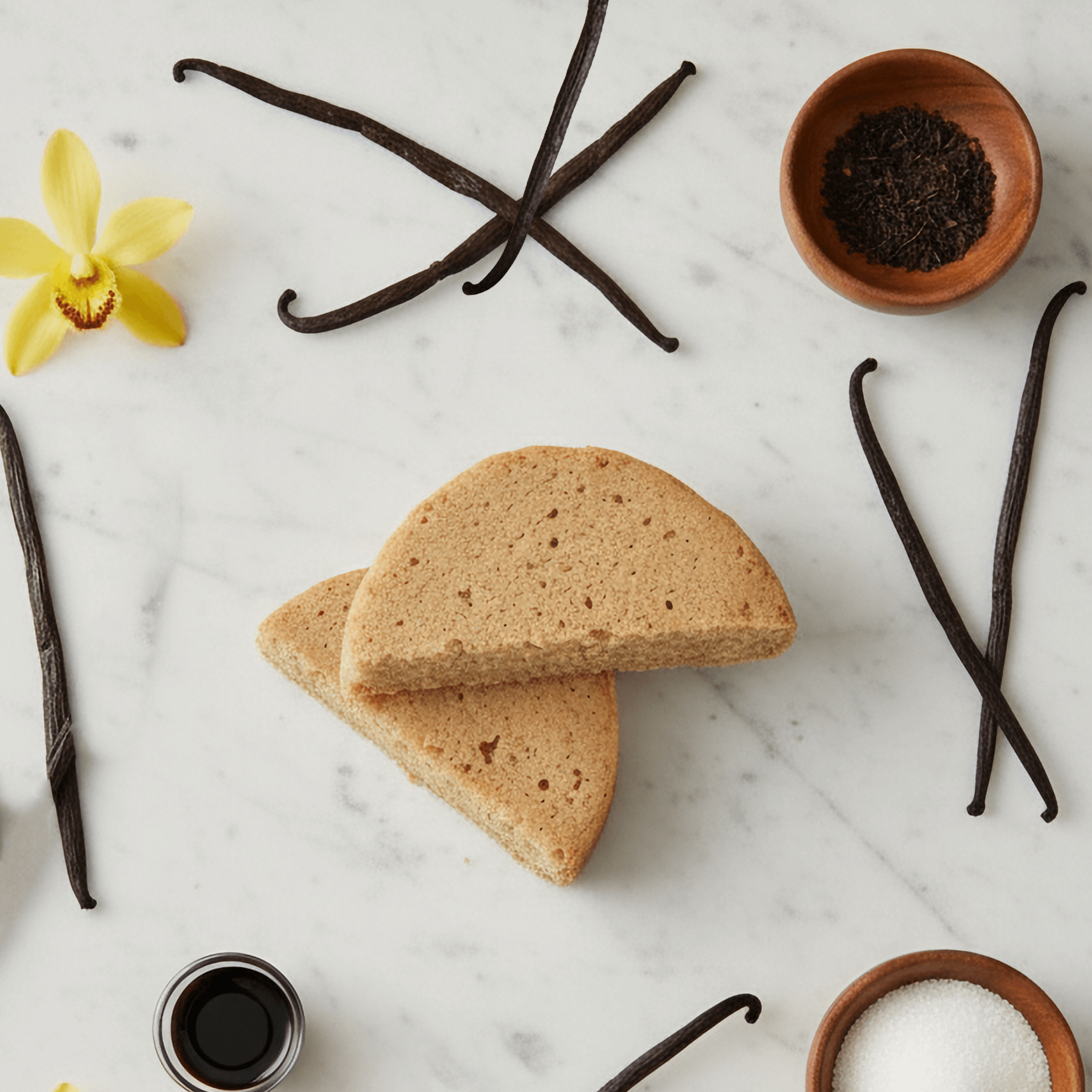 Vanilla Protein Cake Mix slices surrounded by vanilla pods, flowers, and baking ingredients.